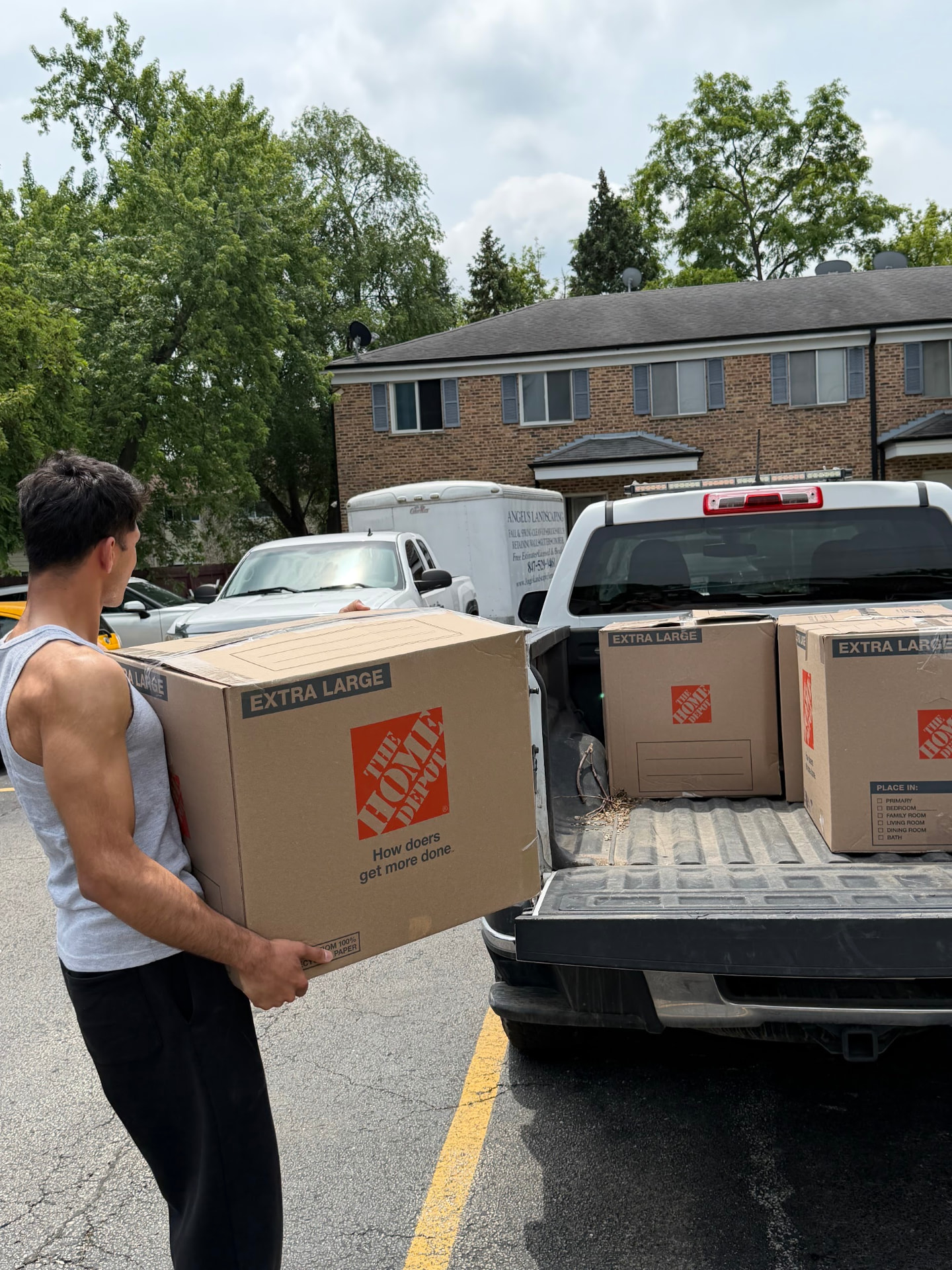 Mover carrying a large Home Depot box to a pickup truck