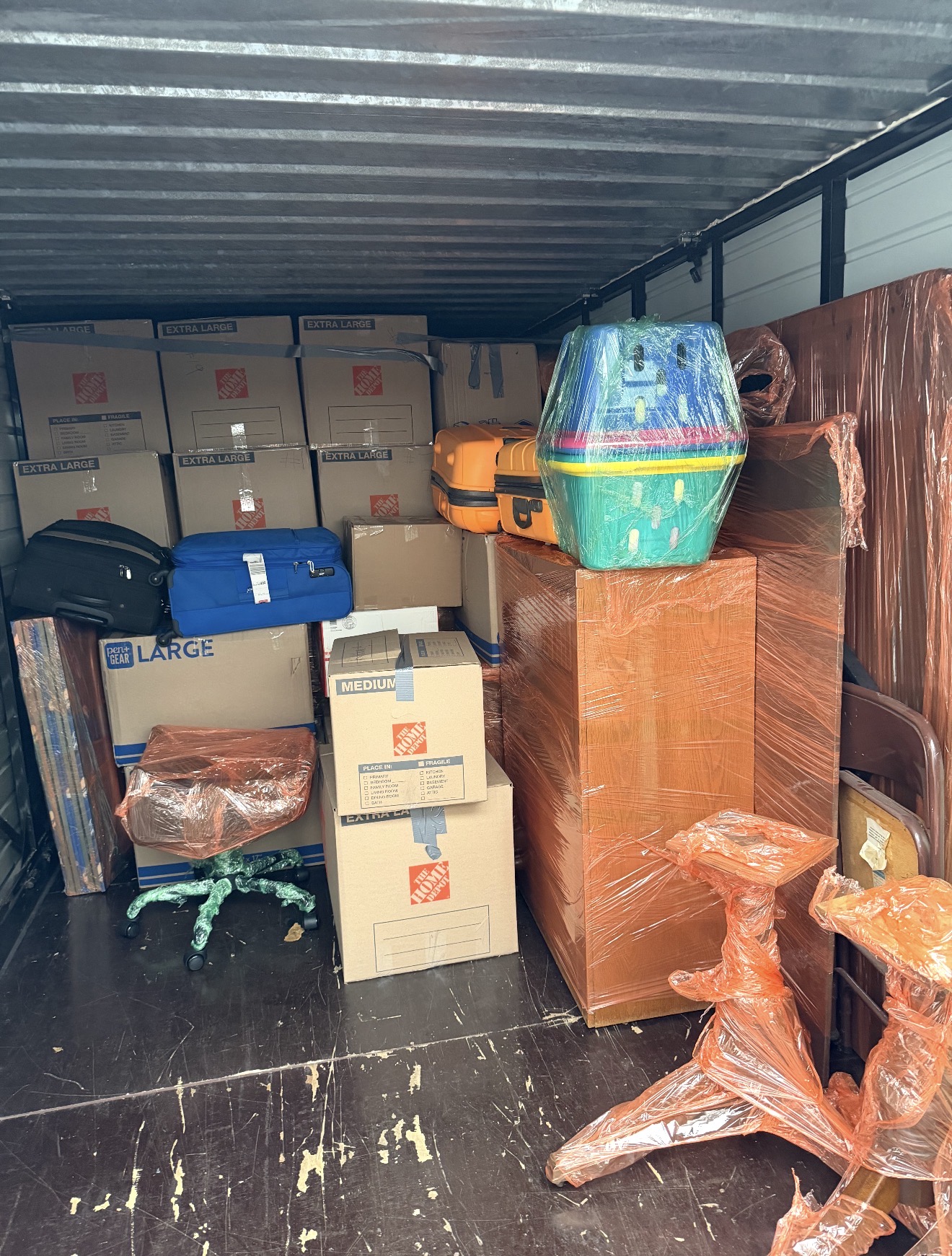Tightly packed moving truck with boxes, furniture, and luggage wrapped for protection
